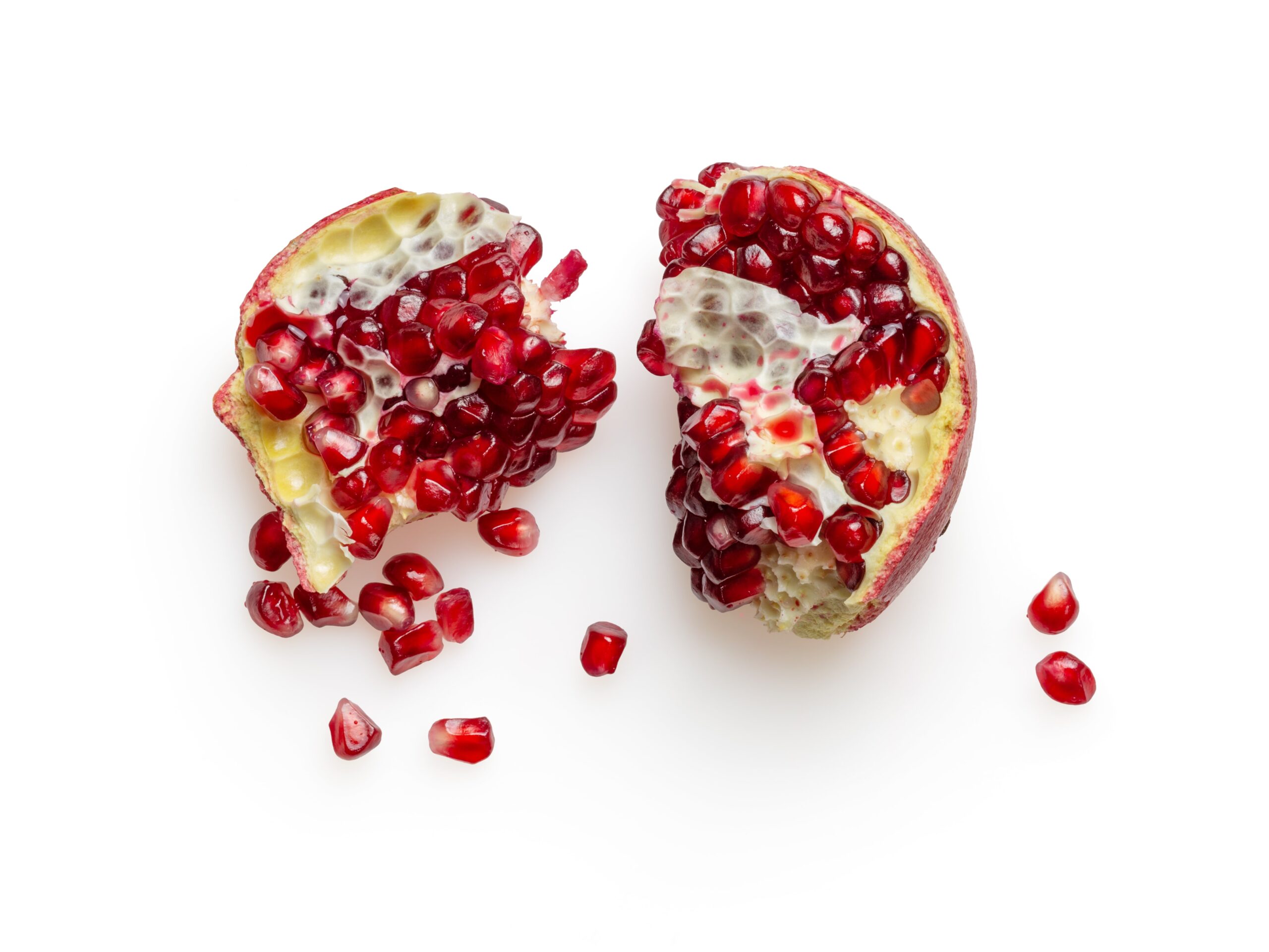A pomegranate cut in half with some seeds displaced